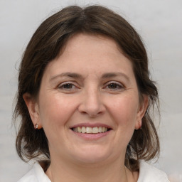 Joyful white adult female with medium  brown hair and grey eyes