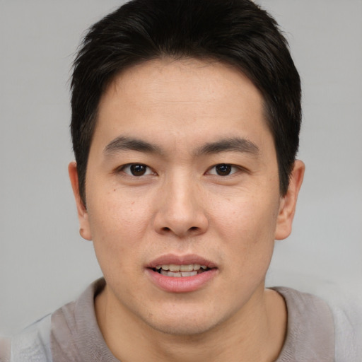 Joyful asian young-adult male with short  brown hair and brown eyes
