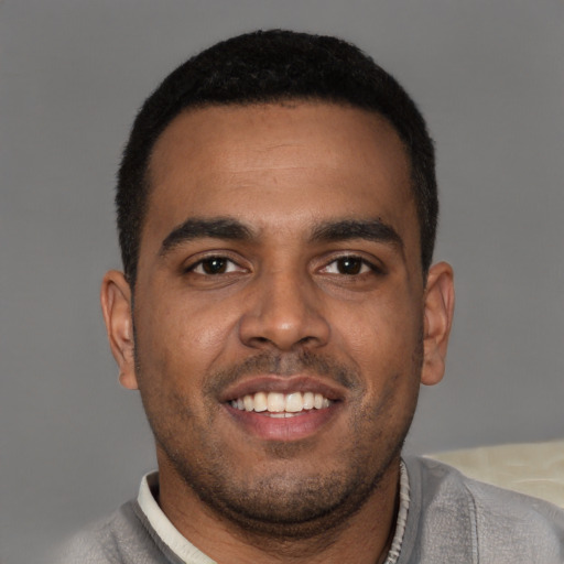Joyful black young-adult male with short  brown hair and brown eyes