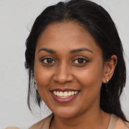 Joyful black young-adult female with long  brown hair and brown eyes