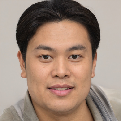 Joyful asian young-adult male with short  brown hair and brown eyes