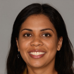 Joyful black young-adult female with long  brown hair and brown eyes