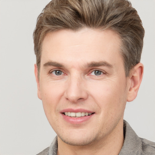 Joyful white adult male with short  brown hair and grey eyes