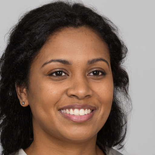 Joyful black young-adult female with long  brown hair and brown eyes