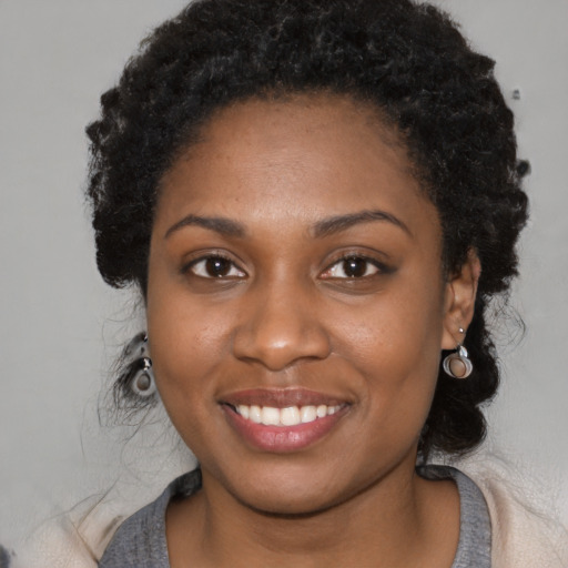 Joyful black young-adult female with long  black hair and brown eyes
