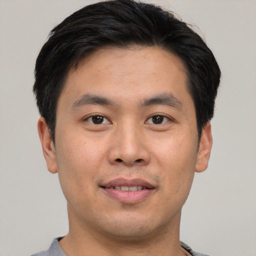 Joyful asian young-adult male with short  brown hair and brown eyes
