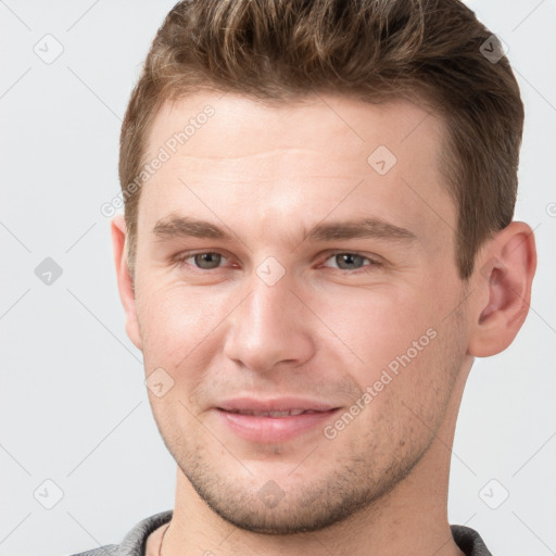 Joyful white young-adult male with short  brown hair and grey eyes