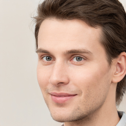 Joyful white young-adult male with medium  brown hair and grey eyes