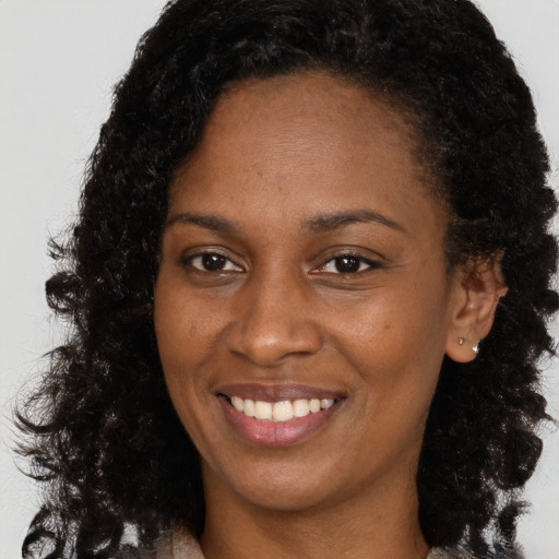 Joyful black young-adult female with long  brown hair and brown eyes