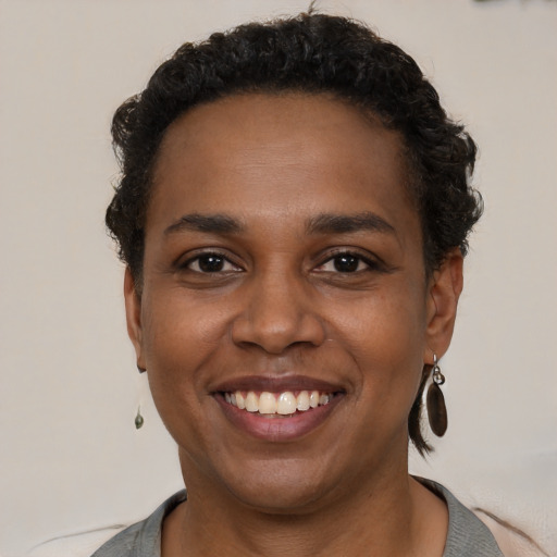 Joyful black young-adult female with short  black hair and brown eyes