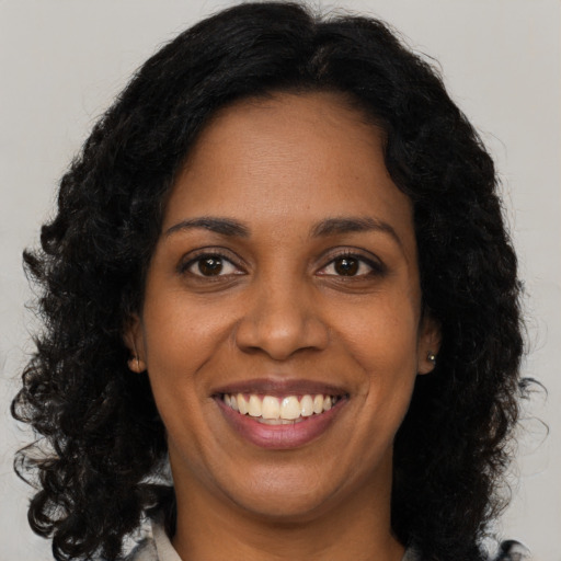 Joyful black young-adult female with long  brown hair and brown eyes