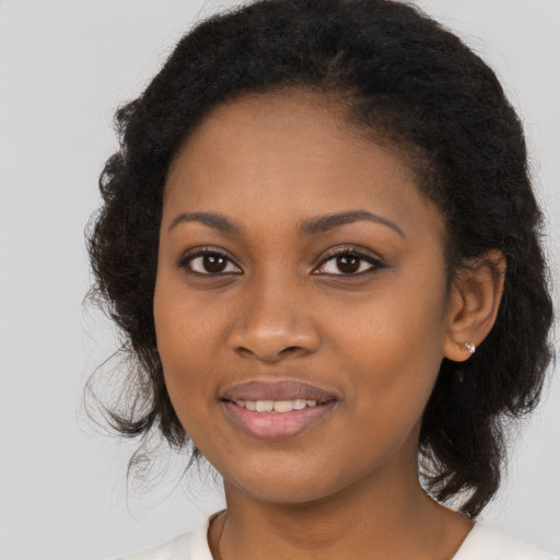 Joyful black young-adult female with long  brown hair and brown eyes