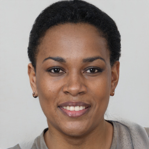 Joyful black young-adult female with short  black hair and brown eyes