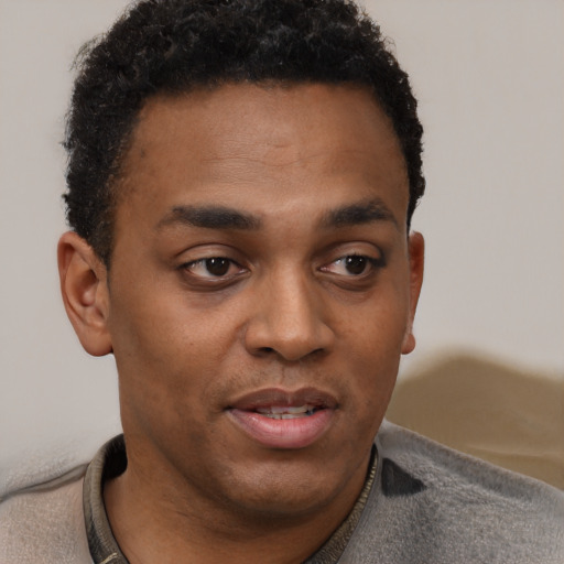 Joyful black young-adult male with short  brown hair and brown eyes