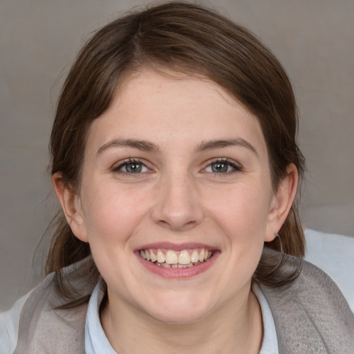 Joyful white young-adult female with medium  brown hair and grey eyes