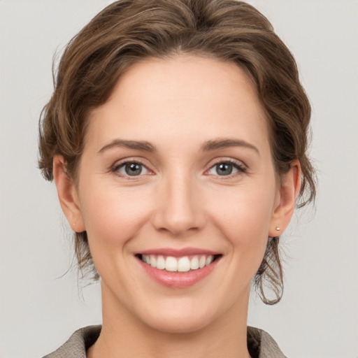 Joyful white young-adult female with medium  brown hair and grey eyes