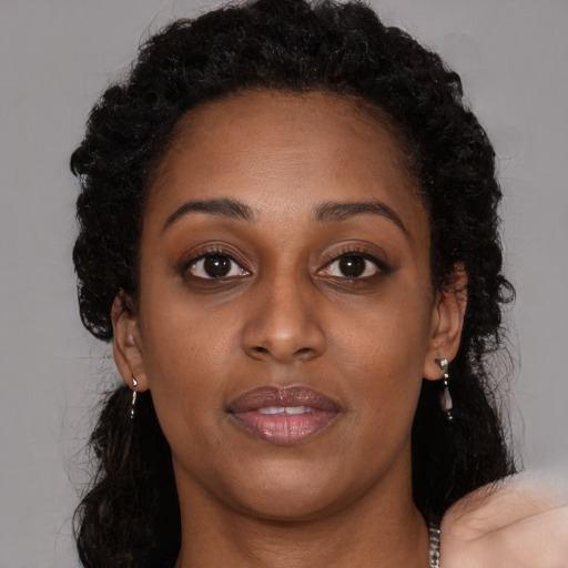 Joyful black young-adult female with long  brown hair and brown eyes