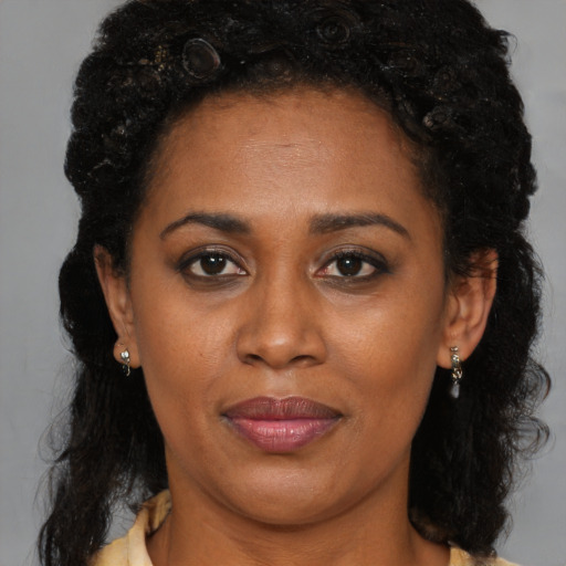 Joyful black adult female with long  brown hair and brown eyes