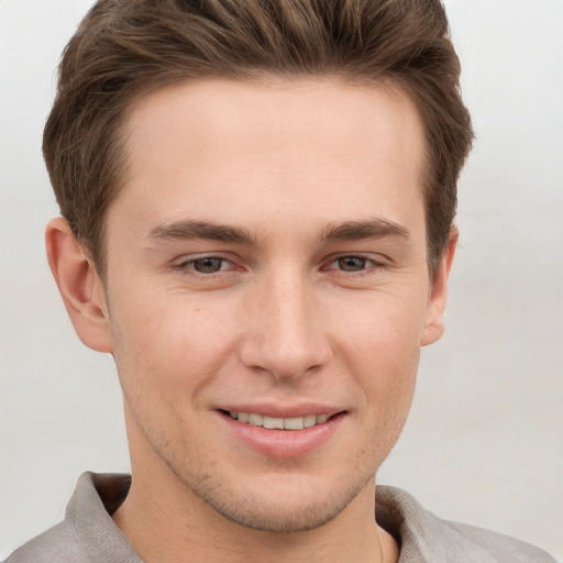 Joyful white young-adult male with short  brown hair and grey eyes