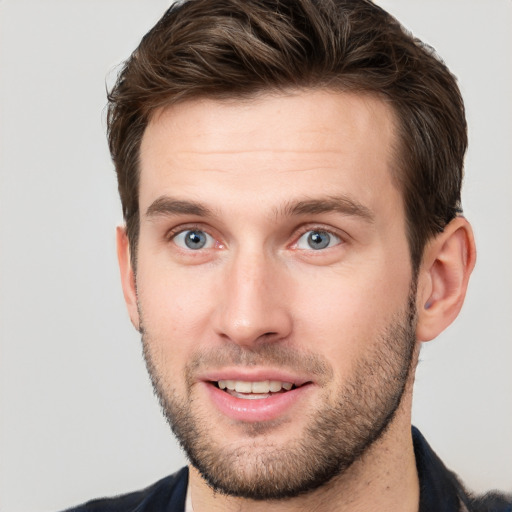 Joyful white young-adult male with short  brown hair and grey eyes