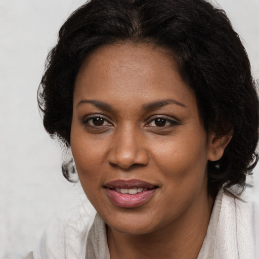 Joyful black young-adult female with long  brown hair and brown eyes