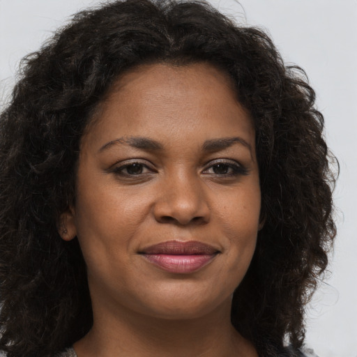 Joyful black young-adult female with long  brown hair and brown eyes