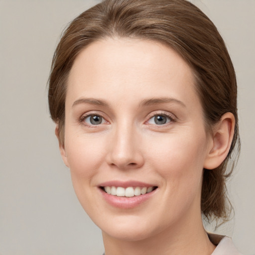 Joyful white young-adult female with medium  brown hair and grey eyes