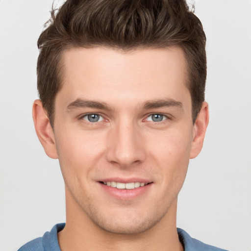 Joyful white young-adult male with short  brown hair and grey eyes