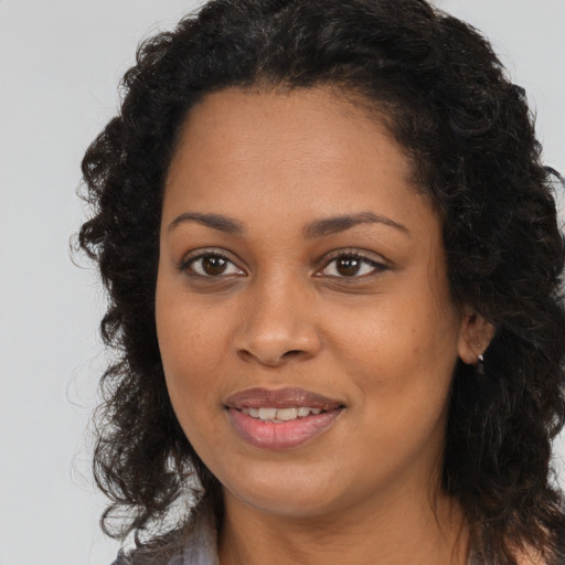 Joyful black young-adult female with long  brown hair and brown eyes