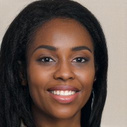 Joyful black young-adult female with long  brown hair and brown eyes