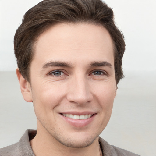 Joyful white young-adult male with short  brown hair and grey eyes