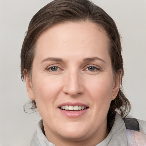 Joyful white young-adult female with medium  brown hair and grey eyes