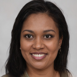 Joyful black young-adult female with long  brown hair and brown eyes