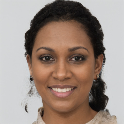 Joyful black young-adult female with long  black hair and brown eyes