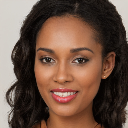 Joyful black young-adult female with long  brown hair and brown eyes