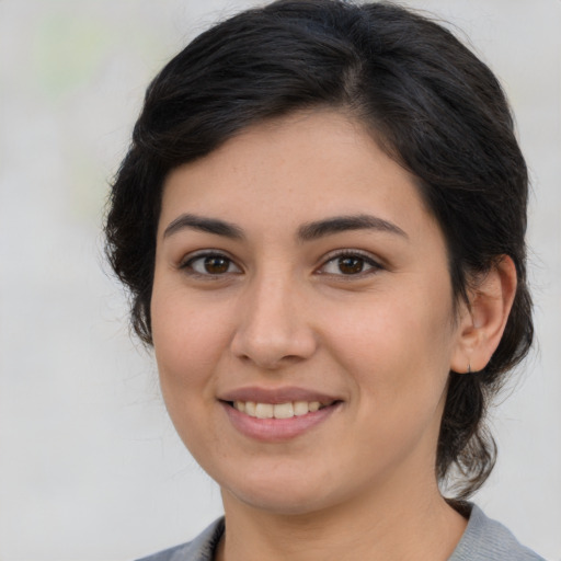 Joyful latino young-adult female with medium  brown hair and brown eyes