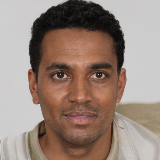 Joyful black young-adult male with short  black hair and brown eyes