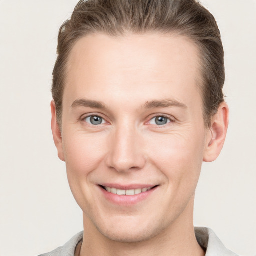 Joyful white young-adult male with short  brown hair and grey eyes