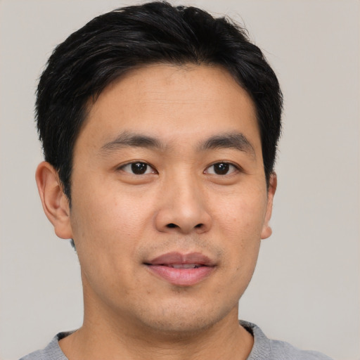 Joyful asian young-adult male with short  black hair and brown eyes