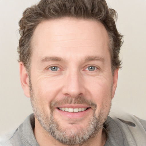 Joyful white adult male with short  brown hair and grey eyes