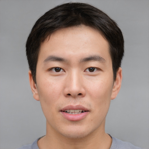 Joyful asian young-adult male with short  brown hair and brown eyes
