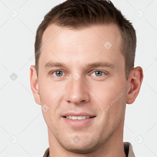 Joyful white young-adult male with short  brown hair and grey eyes