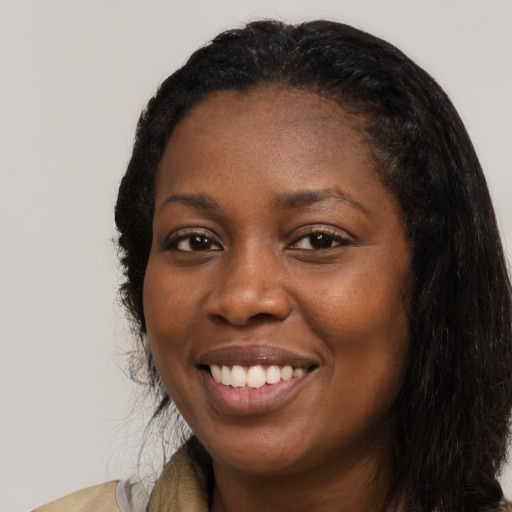 Joyful black young-adult female with long  black hair and brown eyes