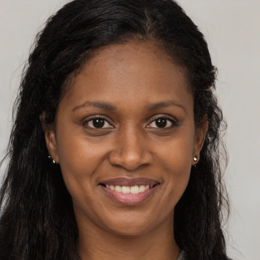Joyful black young-adult female with long  brown hair and brown eyes