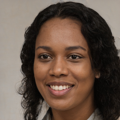 Joyful black young-adult female with long  black hair and brown eyes