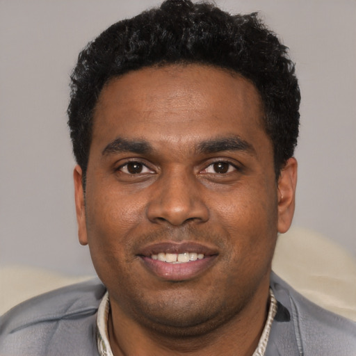 Joyful black young-adult male with short  black hair and brown eyes