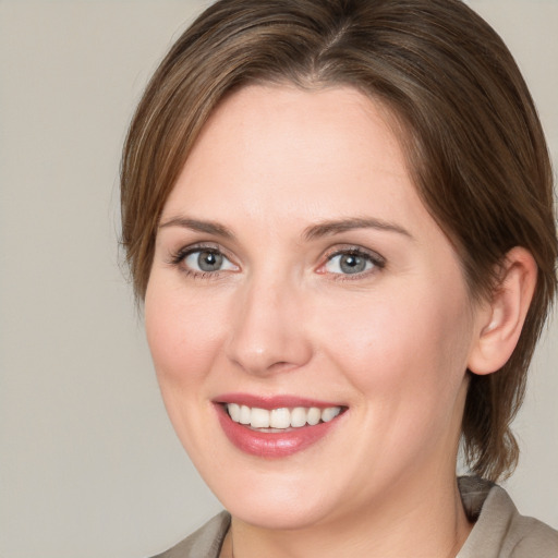 Joyful white young-adult female with medium  brown hair and grey eyes