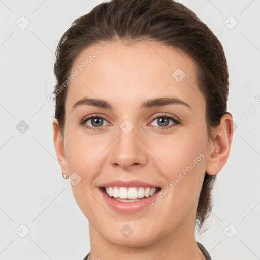 Joyful white young-adult female with medium  brown hair and grey eyes