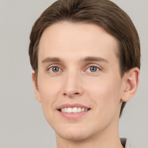 Joyful white young-adult male with short  brown hair and grey eyes