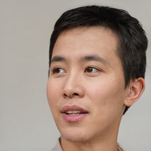 Joyful asian young-adult male with short  black hair and brown eyes